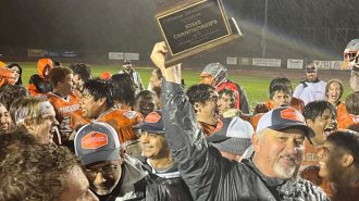 Coach Vic Cooper holds the team's new trophy aloft