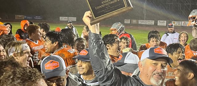 Coach Vic Cooper holds the team's new trophy aloft