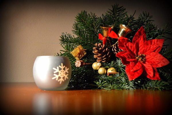 Holiday floral arrangement with a red poinsettia, pine and a snowflake candle holder
